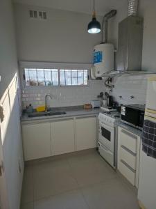 a kitchen with white cabinets and a sink and a stove at Soles de Pergamino in Pergamino