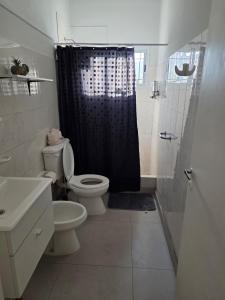 a bathroom with a black shower curtain and a toilet at Soles de Pergamino in Pergamino