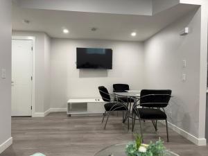 a dining room with a table and chairs and a tv at Cozy Suite Near Airport in YYC
