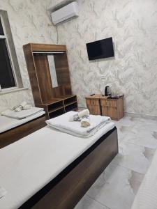 a bedroom with two beds and a tv on the wall at Turg'unTown in Toshkent-Passajir Bekati