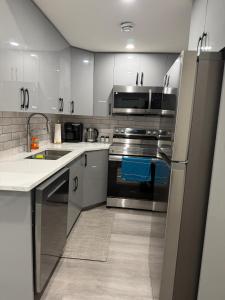a kitchen with white cabinets and stainless steel appliances at Cozy Suite Near Airport in YYC