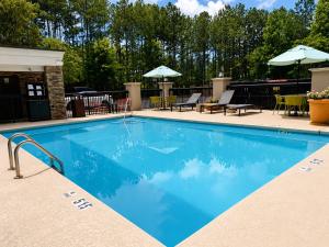 a swimming pool at a resort with chairs and umbrellas at Hampton Inn Cartersville in Cartersville
