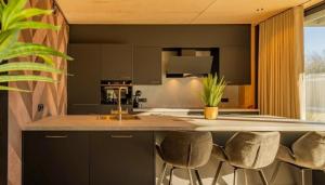 a kitchen with black cabinets and a counter with stools at Forest Villa 8 persons #724 in Maasbree