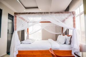a bedroom with a white canopy bed with a window at Kitobo Serenity Resort in Arusha