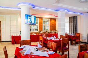 a restaurant with red tables and chairs and a flat screen tv at Kitobo Serenity Resort in Arusha