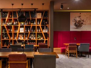 ein Restaurant mit Tischen und Stühlen und einem Regal mit Weinflaschen in der Unterkunft Mercure Gdynia Centrum in Gdynia