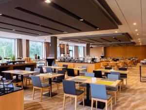 ein Restaurant mit Tischen und Stühlen und einer Küche in der Unterkunft Mercure Gdynia Centrum in Gdynia