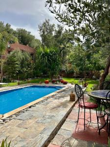 a swimming pool in a yard with a table and chairs at Auberge Le Mouflon in Ouirgane