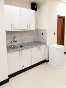 a kitchen with white cabinets and a sink and a refrigerator at We Hotels Islamabad Airport in Islamabad +18 photos