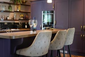a kitchen with a bar with wine glasses and purple cabinets at Kiltumper Lodge in Kilmihil