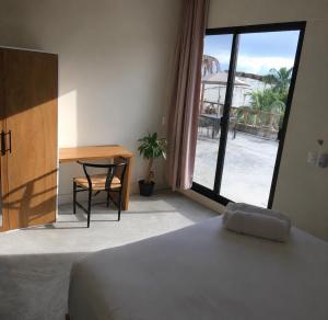 a bedroom with a bed and a desk and a window at Black flamingo in Holbox Island