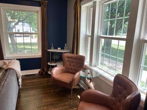 a living room with a couch and chairs and windows at The Legacy House in Topeka +60 photos