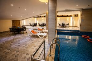 a swimming pool with chairs and a table and a dining room at Medhal Hotel in Jeddah