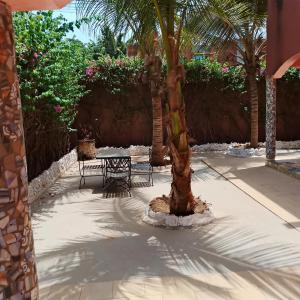 a table and a palm tree in a courtyard at Keur Diédhiou in Saly Portudal