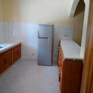a kitchen with a refrigerator and a tile floor at Keur Diédhiou in Saly Portudal +1 photo