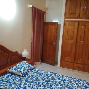 a bedroom with a bed with a blue bedspread and a door at Keur Diédhiou in Saly Portudal