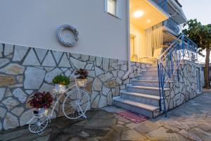 a bike parked next to a stone wall with stairs at Μπλε Rooms & Apartments in Chiliadou
