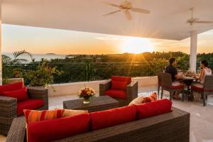 a patio with a couch and people sitting at a table at Luxury Oceanview Penthouse in HDM in Punta Mita