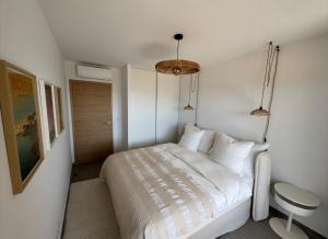 a white bedroom with a bed and a stool in it at Cosi Horizon in Grosseto-Prugna