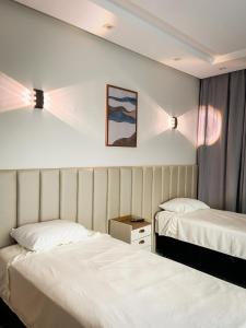 two beds in a hotel room with white sheets at Pousada Acessus Executivo - Cozinha e Lavanderia in Anápolis