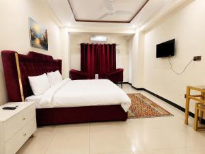a bedroom with a large bed and a red curtain at We Hotels Islamabad Airport in Islamabad