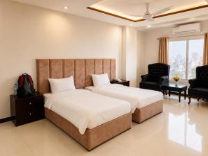 a hotel room with two beds and a chair at We Hotels Islamabad Airport in Islamabad