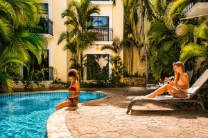 two women sitting around a swimming pool in a hotel at Gran Real Yucatan in Mérida