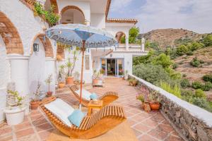a house with a patio with chairs and an umbrella at "The Chill Pad In Cotobro A Boutique Style Studio Where Chillin Is Easy" in Almuñécar