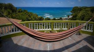 a hammock on a balcony with a view of the ocean at I VIEW - in Long Bay in Long Bay Village