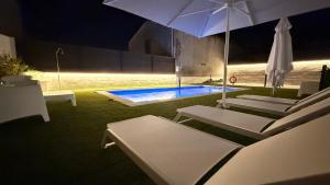 a swimming pool with chairs and an umbrella at Apartamentos Pantón Ribeira Sacra in Ferreira