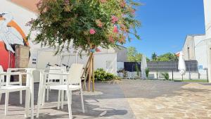 a tree with white chairs next to a building at Apartamentos Pantón Ribeira Sacra in Ferreira