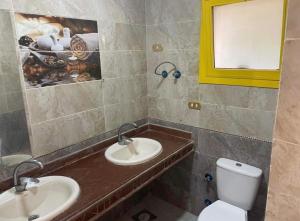 a bathroom with two sinks and a toilet at فيلا بسين خاص in Dawwār Abū Maḩrūs +10 photos
