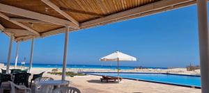 a view of the beach from a patio with an umbrella at فيلا بسين خاص in Dawwār Abū Maḩrūs