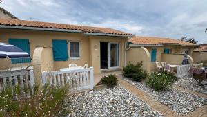 a house with a fence and chairs in front of it at Résidence le patio - Mimizan plage in Mimizan-Plage