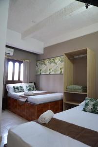 a bedroom with three beds with white sheets at Hotel Lua y Origenes Santa Marta in Santa Marta