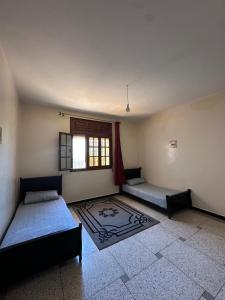 a room with two beds and a window at rez-de-chaussée villa pour famille in Sidi Bouzid