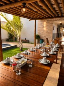 a long wooden table with plates of food on it at Villa Vinci Flat in São Miguel do Gostoso