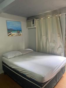 a bed in a small room with a window at Pouso do caiçara suíte fundo do mar in Paraty +2 photos