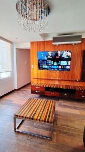 a living room with a large tv and a bench at Luxury Duplex Terrace and Grill in Ica