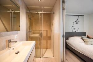 a bathroom with a shower and a sink and a bed at Forest Cube 4 persons #706 in Maasbree