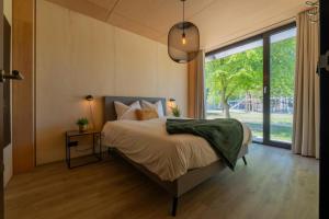 a bedroom with a bed and a large window at Forest Villa 6 persons #1212 in Maasbree