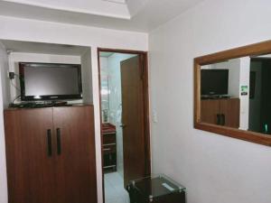 a room with a tv on a cabinet and a mirror at Hotel Apartasuite Normandia in Bogotá