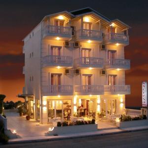 un gran edificio blanco con balcones por la noche en Kalipso en Paralia Katerinis