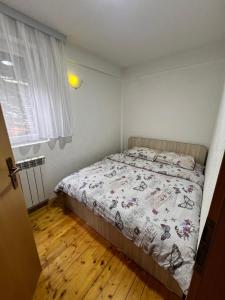 a bedroom with a bed and a window and wooden floors at Villa JETI in Tetovo