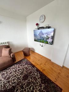 a living room with a couch and a clock on the wall at Villa JETI in Tetovo