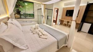 a bedroom with a large white bed and a bath tub at Hotel & Pousada Recanto do Sabiá in Pirapora