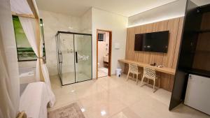 a bathroom with a shower and a television in it at Hotel & Pousada Recanto do Sabiá in Pirapora +55 photos
