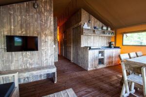 a living room with wooden floors and a tv and a kitchen at Waterlodge 8 persons #WL01 in Maasbree