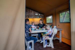a family sitting at a table in a tiny house at Waterlodge 8 persons #WL01 in Maasbree