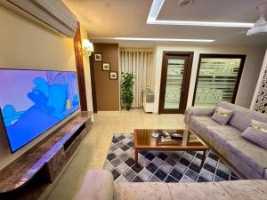 a living room with a couch and a large screen tv at Bella Boutique Hotel Near Centaurus Mall - LMY Hospitality Islamabad in Islamabad